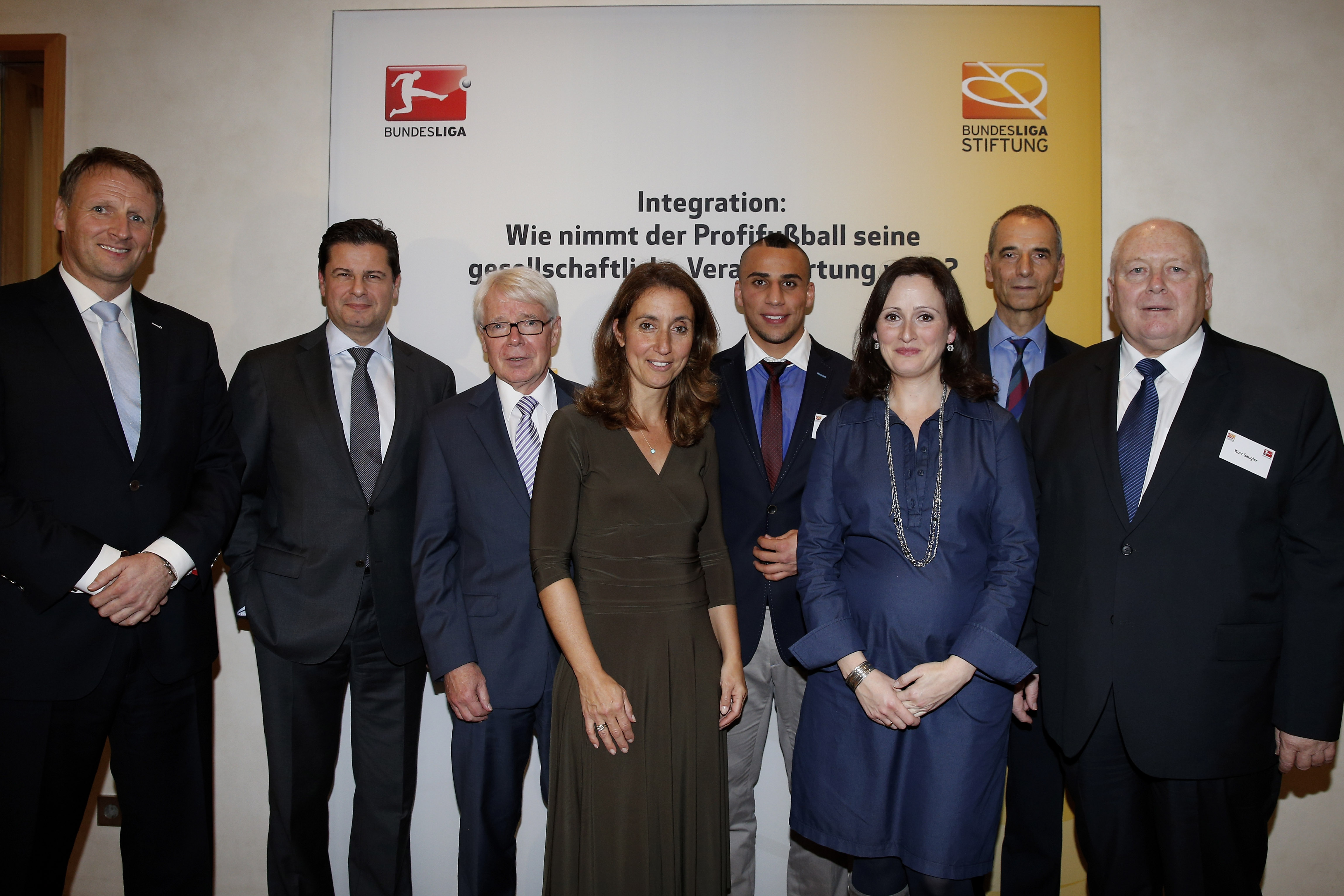 Eine Gruppe von acht Personen steht bei einem Parlamentarischen Abend der Bundesliga und ihrer Stiftung zusammen. Von links nach rechts: Stefan Kiefer, Christian Seifert, Dr. Reinhard Rauball, Aydan Özoguz, Aenis Ben-Hatira, Asli Sevindim, Prof. Michael Wolffsohn und Kurt Gaugler. Sie posieren vor Kameras in einem eleganten Raum.