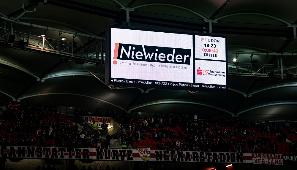 Anzeigetafel im Fußballstadion mit der Aufschrift "Nie wieder" und dem Hinweis auf den Erinnerungstag im Deutschen Fußball.
