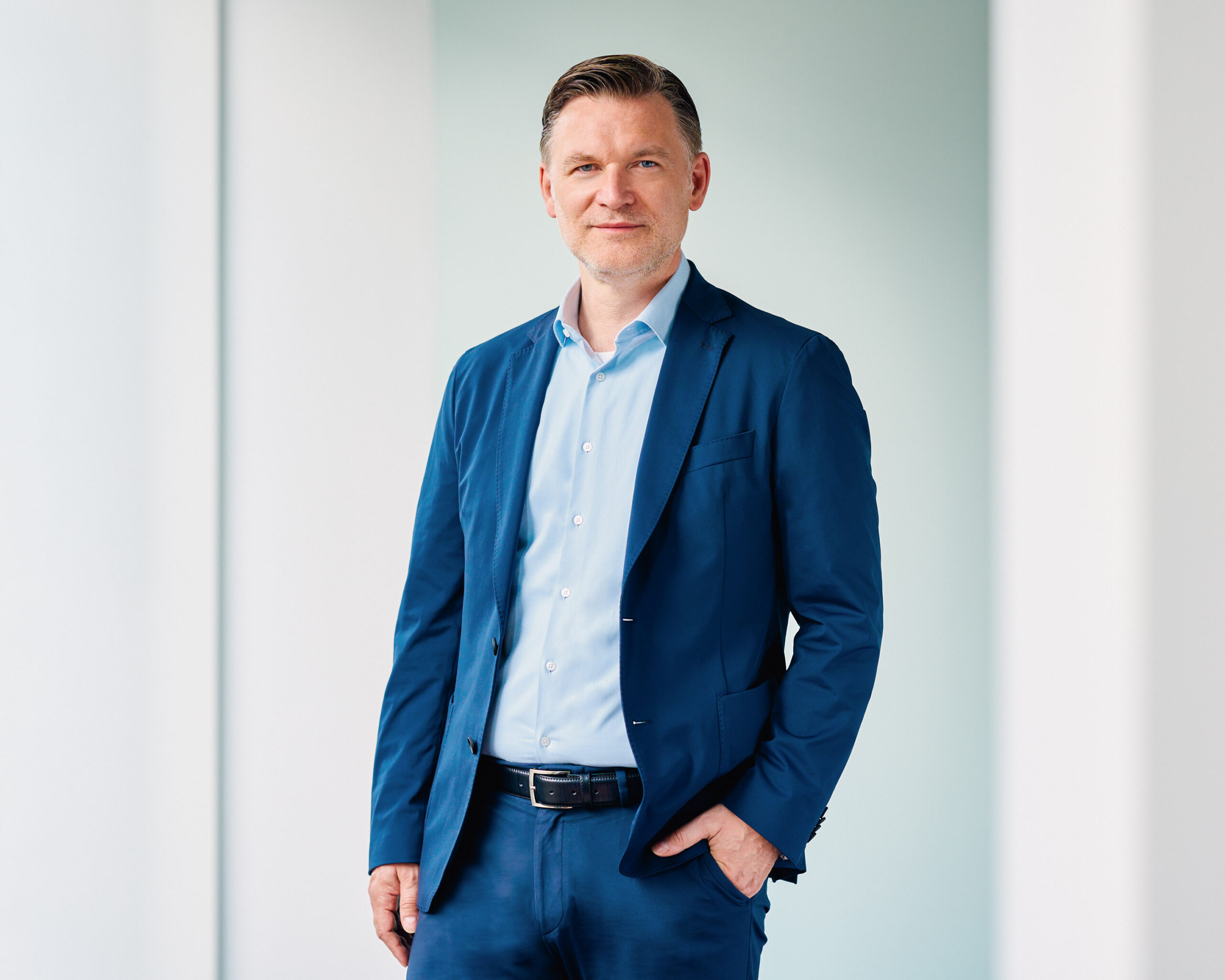 Jörg Degenhart, Mann in blauem Anzug, lächelnd porträtiert.