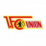 Eine Gruppe von acht Personen in formeller Kleidung sitzt auf einer Bank in einer Sporthalle. Im Hintergrund ist ein großes Banner mit dem Aufdruck "Nürnberg gewinnt" und Kinderbildern zu sehen.