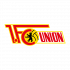 Logo 1. FC Union Berlin Eine Gruppe von acht Personen in formeller Kleidung sitzt auf einer Bank in einer Sporthalle. Im Hintergrund ist ein großes Banner mit dem Aufdruck "Nürnberg gewinnt" und Kinderbildern zu sehen.