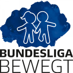 Ein Mann mit rotem Hemd und ein jüngerer Junge im roten Fußballtrikot mit Vereinslogo posieren lächelnd für ein Foto. Im Hintergrund steht ein älterer Junge in einem gelben Trikot.