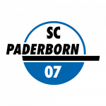 Ein Mann im Anzug zeigt einer Gruppe von Kindern in Sporthosen und Trikots in einer Turnhalle einen Fußball. Die Kinder sitzen, knien oder stehen und halten ebenfalls Fußbälle. Im Hintergrund sind graue Wände und das Parkett des Turnbodens zu sehen.