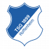 TSG_Standard_Logo_RGB Ein lächelnder Fußballspieler, vermutlich ein Profi, kniet vor zwei jungen Mädchen. Er legt ihnen freundlich die Hand auf die Schulter. Alle drei schauen in die Kamera. Die Mädchen tragen orangefarbene T-Shirts. Im Hintergrund sind weitere Personen und eine Sporthalle erkennbar.