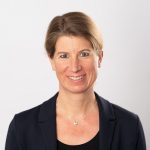 Eine Gruppe Jugendlicher vor einer Wand mit Graffiti-Elementen und den Aufschriften "Lernzentrum", "Schalke macht Schule" und "Denk-Anstoß". Die Jugendlichen lächeln in die Kamera, einige knien oder sitzen vor der Wand.