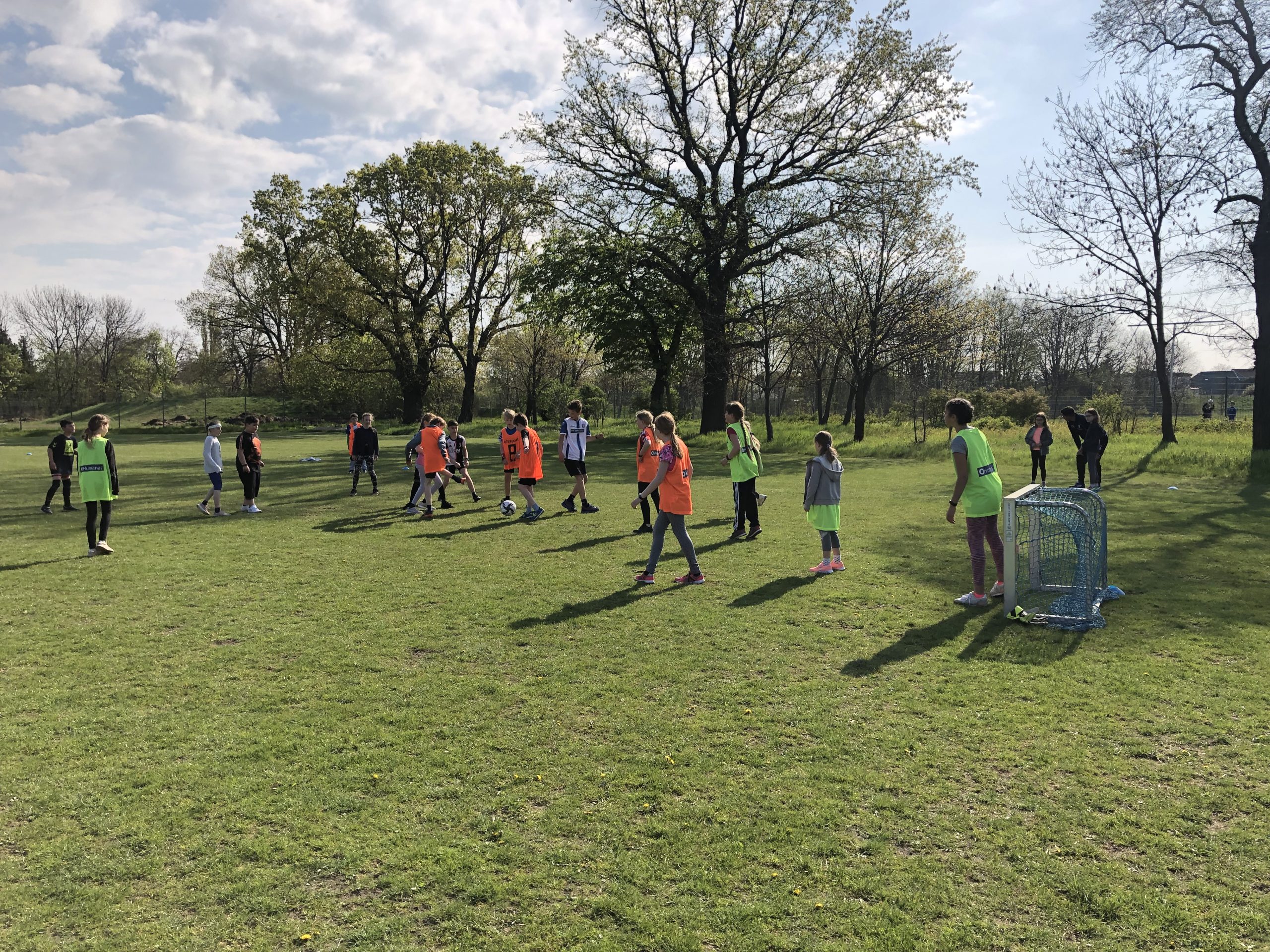 Fußballtorwart in Aktion beim Abschlussturnier "Fußball trifft Kultur" in Frankfurt, springt zur Seite um den Ball zu halten, im Hintergrund weitere Fußballspieler auf dem grünen Rasen.